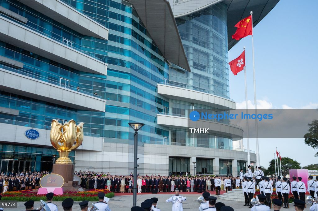 A general wide shot captures dignitaries, officials, and attendees standing at Golden Bauhinia Square as the national and regional flags reach the top of the flagpoles, concluding the formal 77th National Day flag-raising ceremony on October 1, 2026 in Hong Kong. (Photo by Kevin Li/TMHK via Nexpher Images)